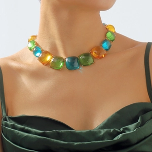 Détail d'un collier de pierres précieuses colorées sur base dorée porté par un mannequin