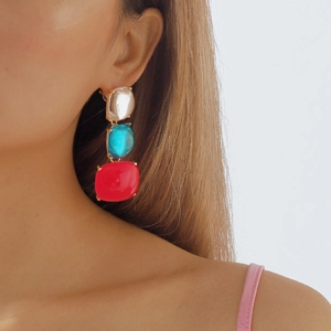 Détail de boucles d'oreilles géométriques avec pierres bleues et rouges sur mannequin