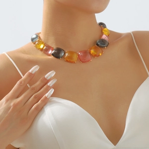 Détail d'un collier géométrique en pierres colorées porté par un mannequin en blanc