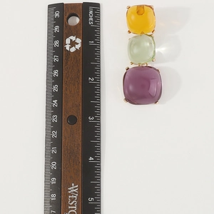 Détail de boucles d'oreilles pierres colorées transparentes avec règle de 2 pouces