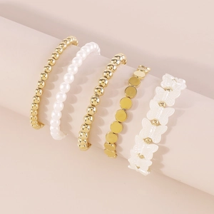 Detalle de un juego de 5 pulseras con cuentas doradas, perlas blancas y mariposa de resina