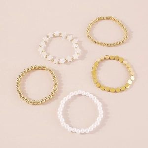 Vista detallada del juego de cinco pulseras con cuentas doradas y perlas blancas