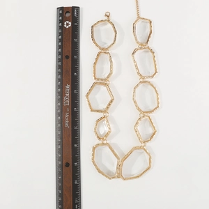 Detail shot of chunky gold alloy necklace with faceted transparent resin geometric charms