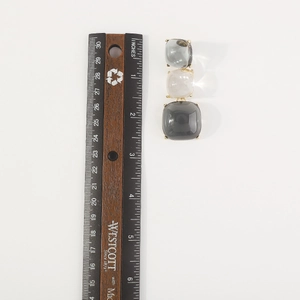 Vue détaillée d'une boucle d'oreille géométrique triple à côté d'une règle de mesure précise