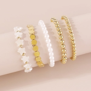 Detalle del juego de 5 pulseras de cuentas doradas con perlas blancas y dijes de estrella