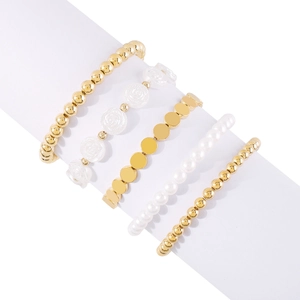 Detalle de un juego de cinco pulseras doradas con perlas blancas y dijes de flores