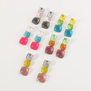 Gros plan sur des boucles d'oreilles carrées en résine colorée avec accents brillants