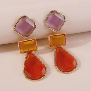 Macro detail of geometric resin earrings with gold frame and colorful drop pendants