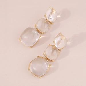 Détail de boucles d'oreilles géométriques dorées avec gouttes en résine transparente