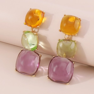 Gros plan de boucles d'oreilles géométriques en résine avec pierres carrées ambre et vert