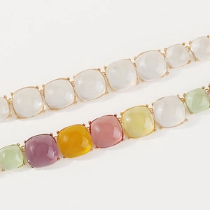 Vue macro de pierres en résine cabochon colorées serties de griffes dorées pour collier