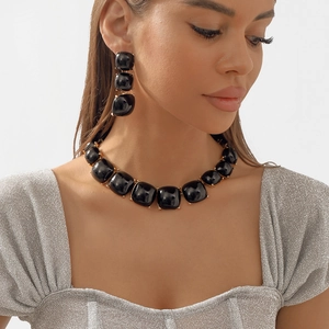 Détail du collier en perles de résine noire bohème et boucles d'oreilles sur modèle