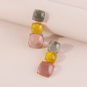 Détail de boucles d oreilles géométriques avec pierres carrées gris jaune et rose