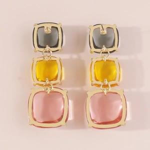 Détail de boucles d'oreilles géométriques avec pierres en résine colorées et cadres dorés
