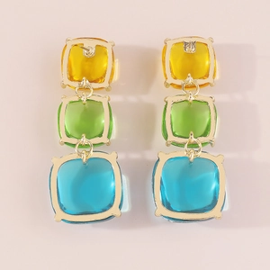 Détail de boucles d'oreilles bohèmes géométriques avec carrés de résine tricolores