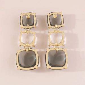 Détail de boucles d'oreilles géométriques en acrylique avec cadre doré et design à trois niveaux