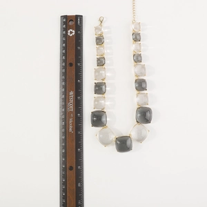 Vue détaillée du collier bohème en perles de résine carrées avec une règle métallique
