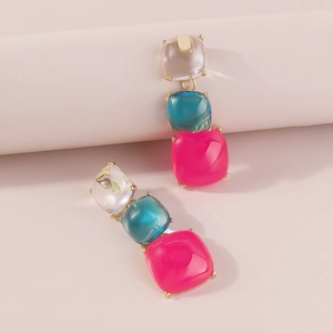 Gros plan de boucles d'oreilles étagées en résine avec des gemmes colorées et vives