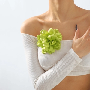 Detail of a large 3D light green satin rose brooch pinned on a white ribbed top