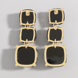 Vue détaillée de boucles d'oreilles pendantes géométriques en métal doré et émail noir