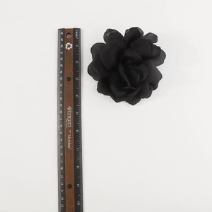 Detailed top view of a large black handmade fabric rose brooch next to a measuring ruler
