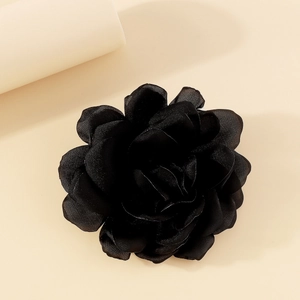 Detail view of a black fabric rose brooch with multi-layered glossy satin petals