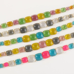 Gros plan de bracelets en pierres carrées colorées avec montures en métal doré