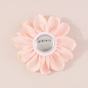 Close-up of pink fabric rose brooch back with silver metal safety pin and white pad