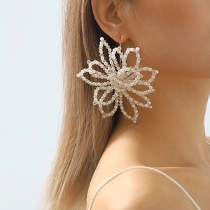 Detail of oversized handmade white pearl and crystal flower earring on model
