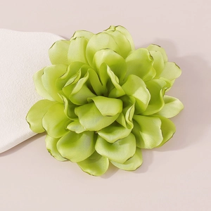 Macro shot of large green fabric camellia flower brooch with layered satin petals