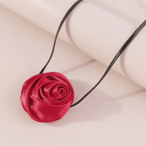 Detail view of large red fabric rose pendant with satin texture and black cord necklace