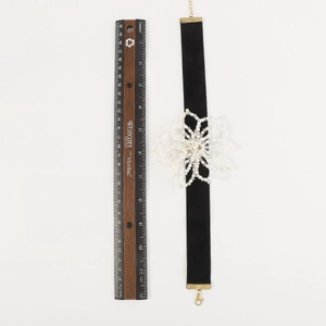 Close-up of black velvet choker with large white bead flower and size measurement
