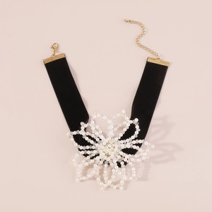 Detail view of a large pearl flower choker with black velvet band and gold clasp