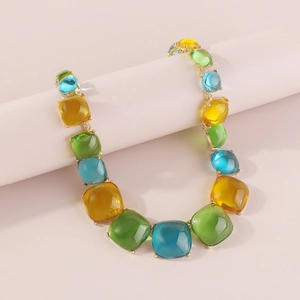 Détail du collier bohème avec pierres en résine ambre, émeraude et azur sur support rose