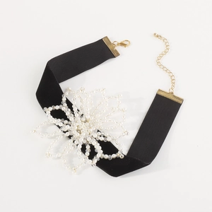Detail of a black velvet choker with large white faux pearl floral centerpiece decoration