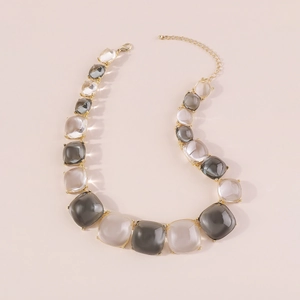 Détail d'un collier géométrique en résine multicolore avec une chaîne dorée ajustable