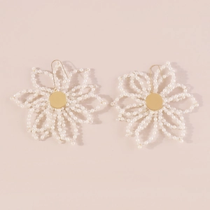 Detail of white beaded floral earrings with gold accents and elegant petal craftsmanship