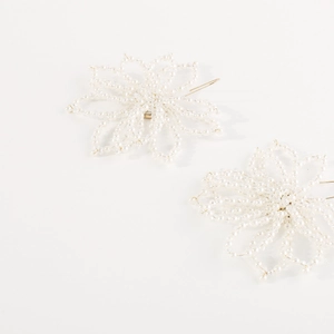 Detail of elegant pearl flower hair pins with gold metal clips on a white background