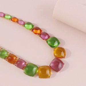 Gros plan d'un collier en résine colorée avec des gemmes carrées vert émeraude