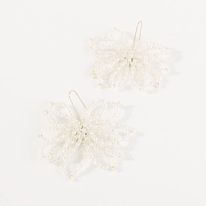 Macro detail of handmade floral beaded earrings with pearl white petals and gold hooks
