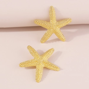Detalle macro de pendientes de estrella de mar dorados con superficie granulada