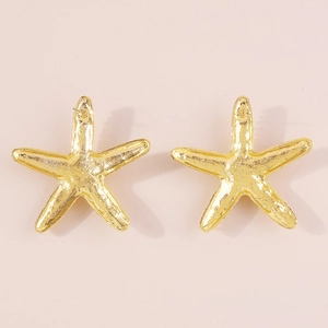 Vista de cerca de pendientes dorados de estrella de mar con textura de metal pulido