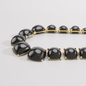 Détail du collier bohème géométrique noir avec montures en métal doré brillant