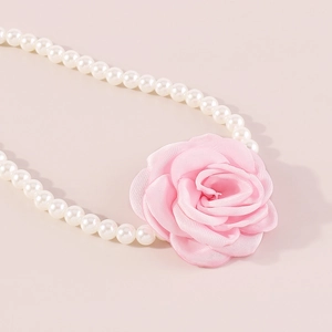 Κοντινό πλάνο κομψού μαργαριταρένιου κολιέ με ένα λεπτομερές ροζ υφασμάτινο τριαντάφυλλο