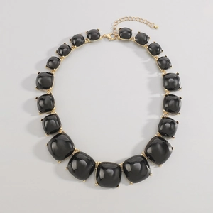 Détails de la base en métal doré et des carrés en résine noire de ce collier ras du cou