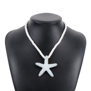 Primer plano del colgante de estrella de mar azul en cordón blanco tejido sobre busto