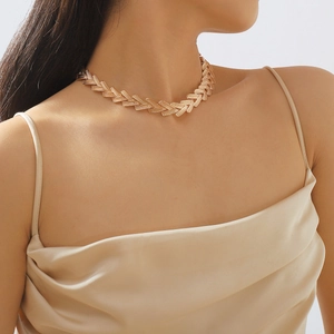 Dettaglio della collana a catena dorata con maglie a V indossata da una modella