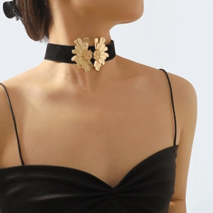 Close-up of black velvet choker featuring symmetrical golden daisy metal charms on neck
