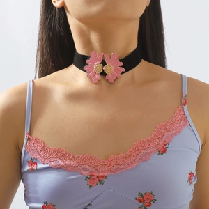 Detailed view of dual pink enamel flowers on a black choker worn by a model