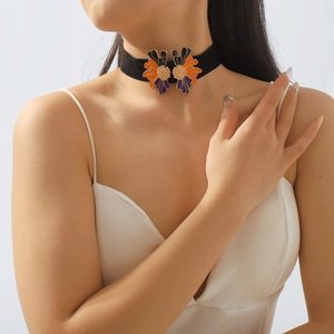 Detail of a black velvet choker with symmetrical orange and purple enamel flowers
